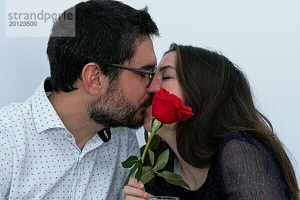 Junges Paar  das sich küsst und eine rote Rose vor sich hat