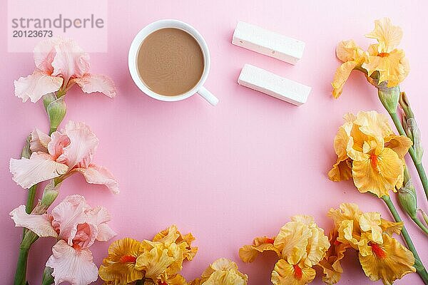 Rosa und orange Irisblüten und eine Tasse Kaffee auf pastellrosa Hintergrund. Morninig  Frühling  Mode Zusammensetzung. Flachlage  Draufsicht  Kopierraum
