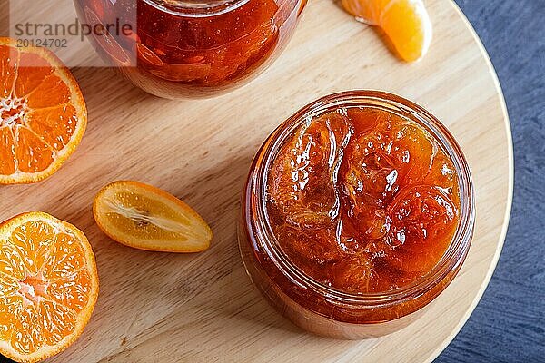 Mandarinen und Kumquatmarmelade in einem Glas mit frischen Früchten auf einem schwarzen Holztisch. Hausgemacht  Nahaufnahme  Draufsicht