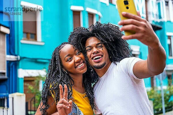 Afrikanisches Paar gestikulieren Erfolg ein Selfie in einer bunten Straße nehmen