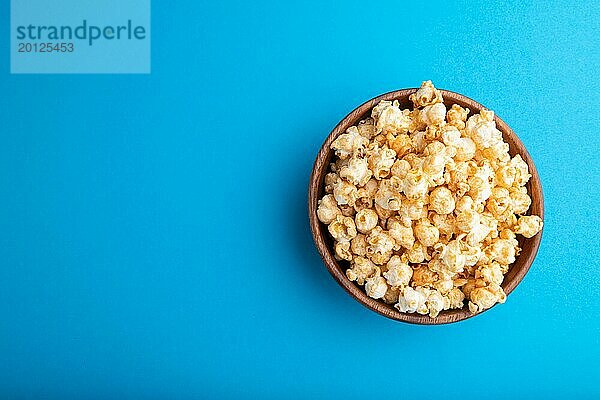 Popcorn mit Karamell in einer Holzschale auf einem pastellblauen Hintergrund. Draufsicht  flat lay  copy space