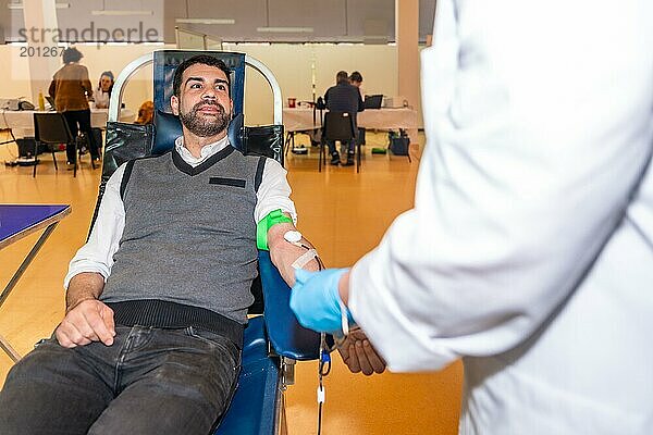 Mann und Krankenschwester unterhalten sich in einem Blutspendezentrum während der Blutentnahme in aller Ruhe