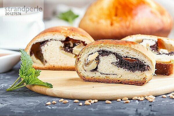 Hausgemachte Hefebrötchen mit Mohn und Honig auf einem hölzernen Küchenbrett auf einem schwarzen Betonhintergrund. Seitenansicht. Nahaufnahme  selektiver Fokus