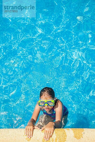 Glückliches Mädchen mit Schwimmbrille entspannt sich im Schwimmbad