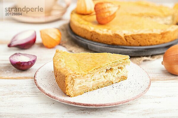 Herbstlicher Zwiebelkuchen und Tasse Kaffee auf weißem Holzhintergrund und Leinentextil. Seitenansicht  Nahaufnahme  selektiver Fokus