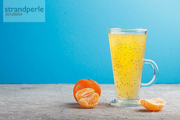 Glas Mandarine orangefarbenen Getränk mit Basilikum Samen auf einem grauen und blauen Hintergrund. Morninig  Frühling  gesundes Getränk Konzept. Seitenansicht  Kopie Raum