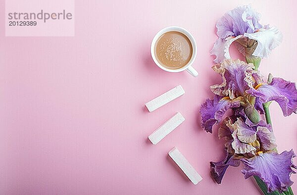 Lila Irisblüten und eine Tasse Kaffee auf pastellrosa Hintergrund. Morninig  Frühling  Mode Zusammensetzung. Flachlage  Draufsicht  Kopierraum