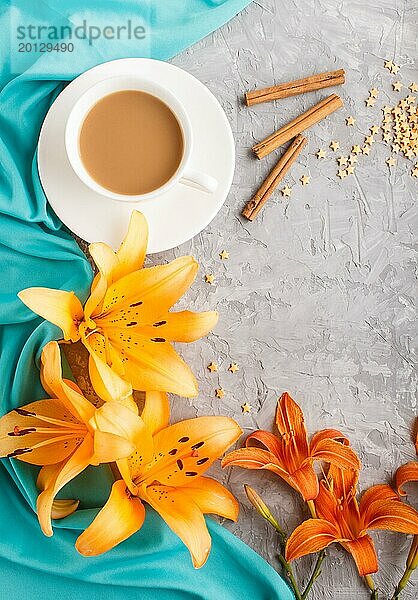Orange Taglilie und Lavendelblüten und eine Tasse Kaffee auf einem grauen Betonhintergrund  mit blauem Textil. Morninig  Frühling  Mode Zusammensetzung. Flachlage  Draufsicht  Kopierraum