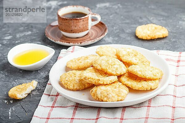 Traditionelle japanische Reis Chips Kekse mit Honig und Sojasauce auf einem weißen Keramikteller und eine Tasse Kaffee auf einem schwarzen Beton Hintergrund. Seitenansicht  Nahaufnahme  selektiver Fokus