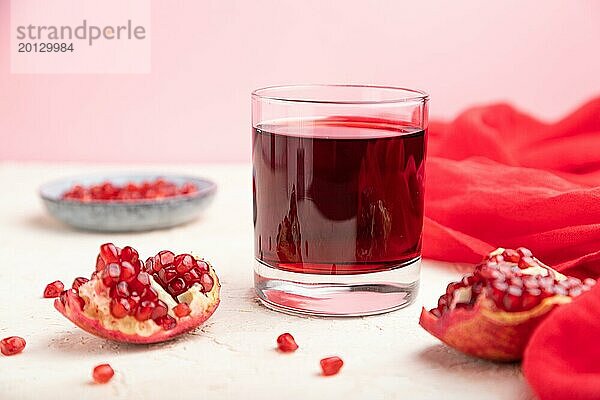 Glas Granatapfelsaft auf weißem und rosa Hintergrund mit rotem Stoff. Seitenansicht  Nahaufnahme  selektiver Fokus