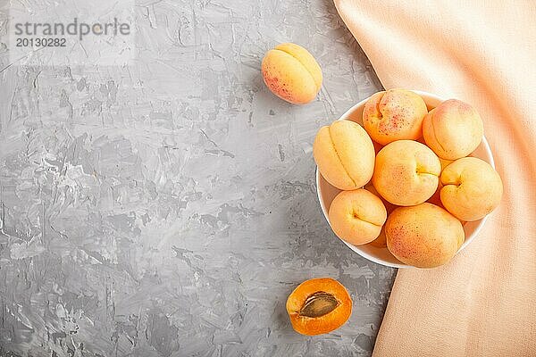 Frische orangefarbene Aprikosen in weißer Schale auf grauem Betonhintergrund. Draufsicht  Kopierraum  Flat Lay
