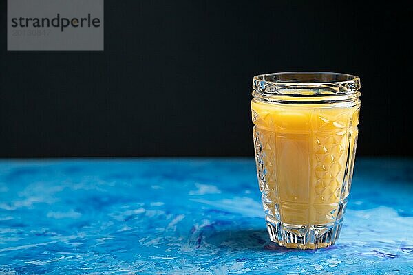 Glas Orangensaft auf einem schwarzen und blauen Hintergrund. Hartes Licht  Kontrast. Seitenansicht  Kopierraum