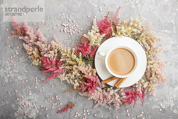 Rosa und rote Astilbe Blumen und eine Tasse Kaffee auf einem grauen Beton Hintergrund. Morninig  Frühling  Mode Zusammensetzung. Flachlage  Draufsicht