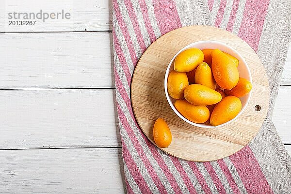 Kumquats in einem weißen Teller auf einem weißen hölzernen Hintergrund  Draufsicht  flat lay  copy space