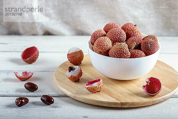 Lychee in einem weißen Teller auf weißem Holzuntergrund  Nahaufnahme