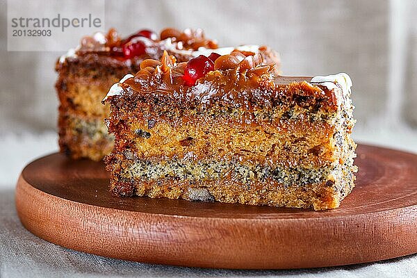 Ein Stück Kuchen mit Karamellcreme und Mohn auf einem hölzernen Küchenbrett. Nahaufnahme  selektiver Fokus  weißer Hintergrund