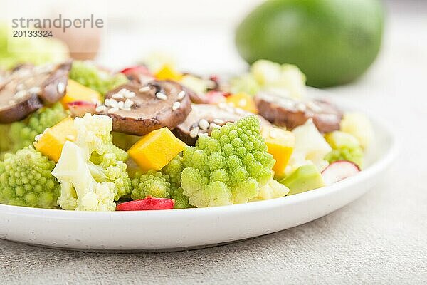 Vegetarischer Salat aus Romanesco Kohl  Champignons  Preiselbeeren  Avocado und Kürbis auf weißem Holzhintergrund und Leinentuch. Seitenansicht  Nahaufnahme  selektiver Fokus