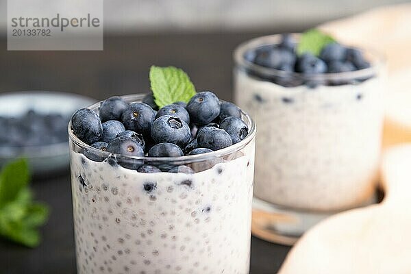 Joghurt mit Heidelbeeren und Chia im Glas auf schwarzem Betonhintergrund und orangefarbenem Leinenstoff. Seitenansicht  Nahaufnahme