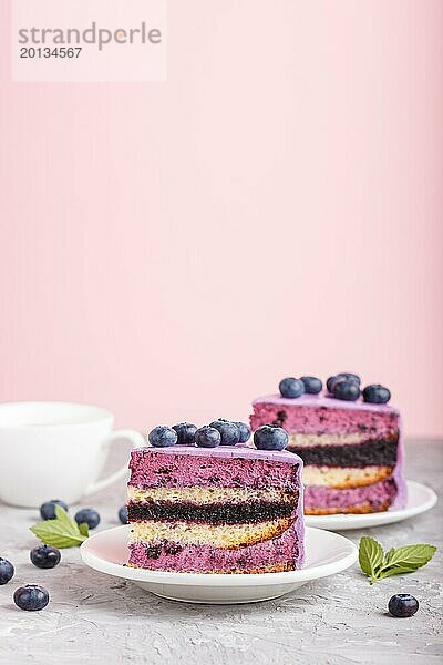 Hausgemachter Kuchen mit Soufflé Creme und Blaubeermarmelade mit Tasse Kaffee und frischen Blaubeeren auf grauem und rosa Hintergrund. Seitenansicht  selektiver Fokus  Kopierraum