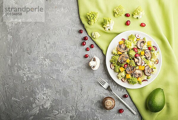 Vegetarischer Salat aus Romanesco Kohl  Champignons  Preiselbeeren  Avocado und Kürbis auf grauem Betonhintergrund und grünem Textil. Draufsicht  Kopiervorlage  Flat Lay