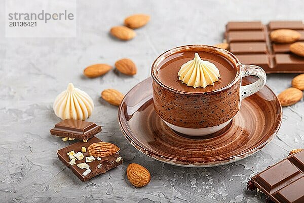Tasse heiße Schokolade und Stücke von Milchschokolade mit Mandeln auf einem grauen Betonhintergrund. Seitenansicht  Nahaufnahme  selektiver Fokus