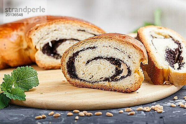 Hausgemachte Hefebrötchen mit Mohn und Honig auf einem hölzernen Küchenbrett auf einem schwarzen Betonhintergrund. Seitenansicht. Nahaufnahme  selektiver Fokus