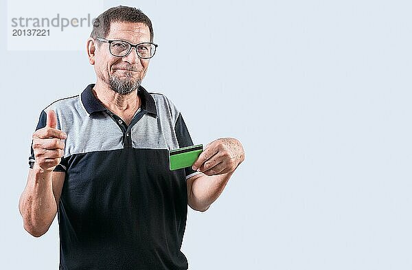 Senior Mann mit Kreditkarte macht Geld Geste mit den Fingern  isoliert. Ältere Menschen halten Kreditkarte machen Geld Geste  lächelnd in die Kamera