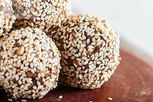 Energiekugelkuchen mit Mandeln  Sesam  Cashew  Walnüssen  Datteln und gekeimtem Weizen auf Holzbrett  Seitenansicht  Nahaufnahme