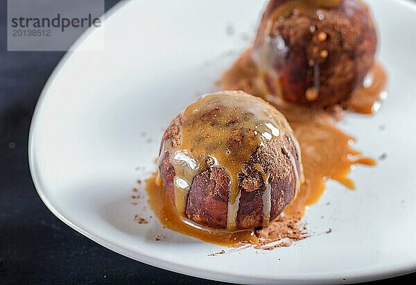 Energy Balls Kuchen mit Schokolade und Karamell auf weißem Teller auf schwarzem Hintergrund. selektiver Fokus  Nahaufnahme