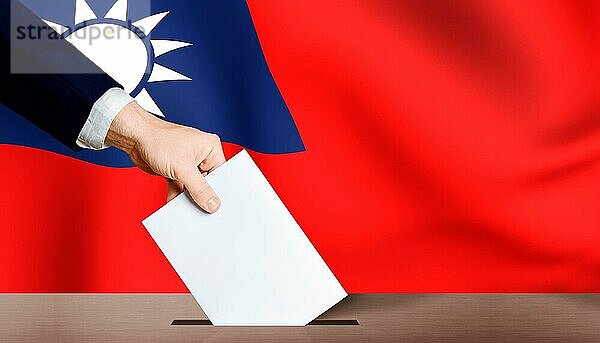 Hand hält Stimmzettel in Wahlurne mit Taiwan Flagge im Hintergrund. Taiwan Präsidentschaftswahlen