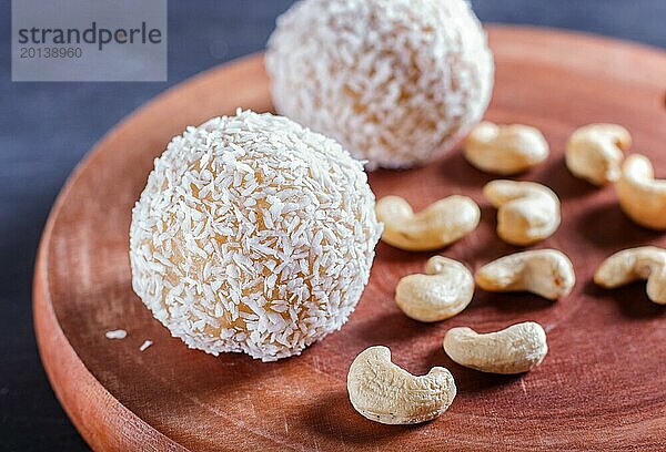 Energy Balls Kuchen mit Kokosnuss und Cashew auf Holzbrett auf schwarzem Hintergrund. selektiver Fokus  Nahaufnahme