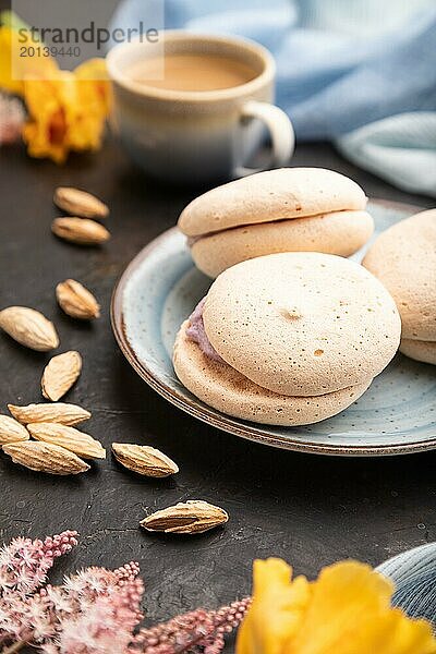 Meringues Kuchen mit einer Tasse Kaffee auf einem schwarzen Betonhintergrund und blauem Leinentuch. Seitenansicht  Nahaufnahme  selektiver Fokus