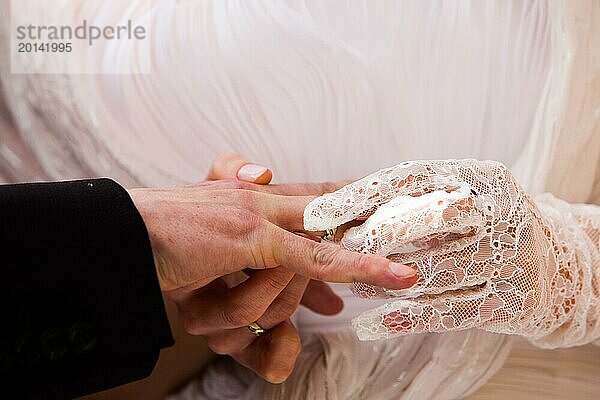 Die Braut steckt den Ehering an den Finger des Bräutigams