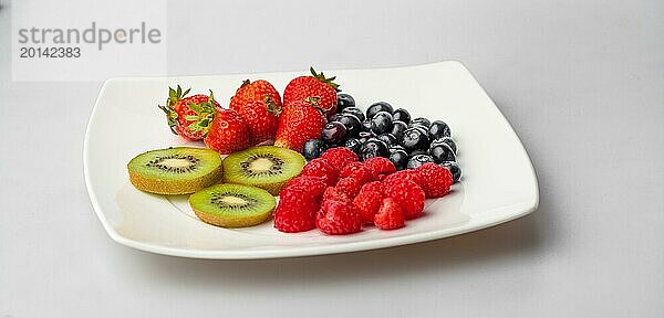 Kiwi  Heidelbeeren  Erdbeeren und Himbeeren auf einem weißen Teller