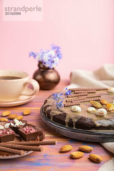 Hausgemachte Schokolade Brownie Kuchen mit Karamell Creme und Mandeln mit Tasse Kaffee auf einem farbigen und rosa Hintergrund und Leinen Textil. Seitenansicht  Kopierraum  selektiver Fokus