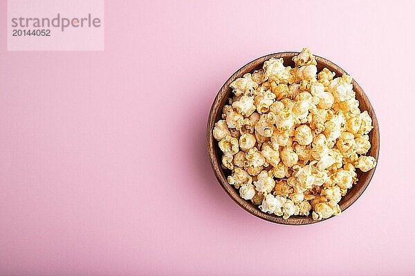 Popcorn mit Karamell in einer Holzschale auf einem pastellrosa Hintergrund. Draufsicht  Flat Lay  Kopierbereich