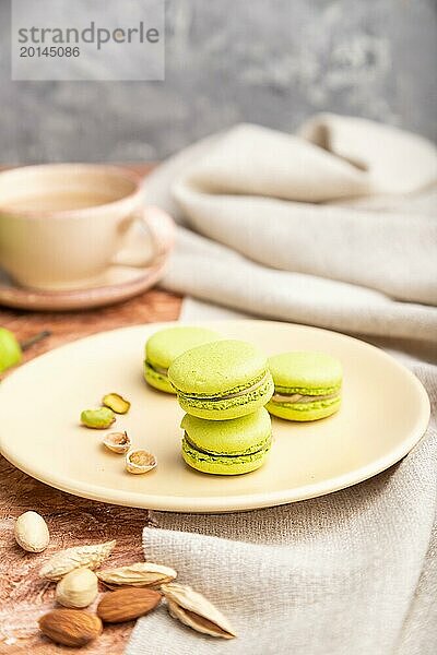 Grüne Macarons oder Makronen Kuchen mit Tasse Kaffee auf einem braunen Beton Hintergrund und Leinen Textil. Seitenansicht  Nahaufnahme  selektiver Fokus