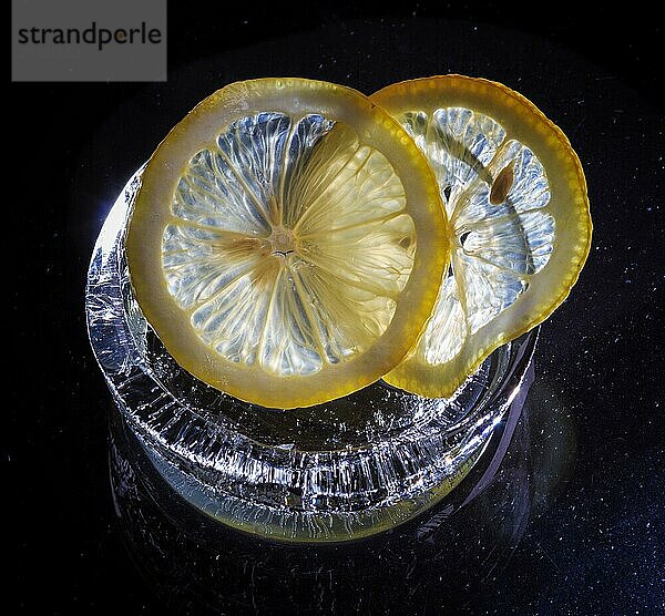 Transparente Scheiben von frischen Orangen und Zitronen auf dem Glas mit Eis