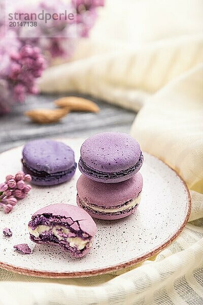 Lila Macarons oder Makronen Kuchen mit Tasse Kaffee auf einem grauen hölzernen Hintergrund und weißem Leinen Textil. Seitenansicht  Nahaufnahme  selektiver Fokus