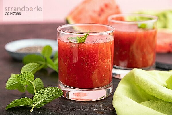 Wassermelonensaft mit Chiasamen und Minze im Glas auf einem schwarzen Betonhintergrund mit grünem Textil. Gesundes Getränk Konzept. Seitenansicht  Nahaufnahme  selektiver Fokus