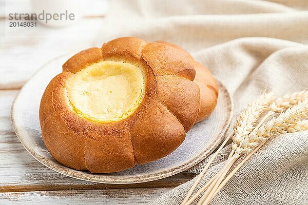 Saures Sahnebrötchen mit Tasse Kaffee auf weißem Holzhintergrund und Leinenstoff. Seitenansicht  Nahaufnahme  selektiver Fokus