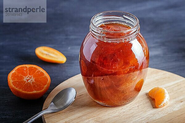 Mandarinen und Kumquatmarmelade in einem Glas mit frischen Früchten auf einem schwarzen Holztisch. Hausgemacht  Kopierraum  Nahaufnahme