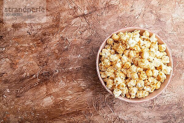 Popcorn mit Karamell in Keramikschale auf braunem Betonhintergrund. Draufsicht  flat lay  copy space