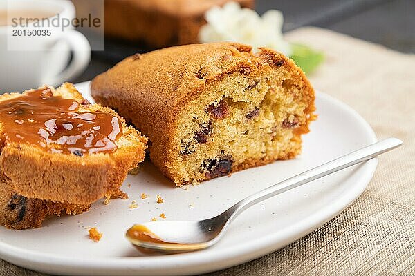 Hausgemachter Kuchen mit Rosinen  Mandeln  weichem Karamell und einer Tasse Kaffee auf einem schwarzen Betonhintergrund und Leinenstoff. Seitenansicht  Nahaufnahme  selektiver Fokus