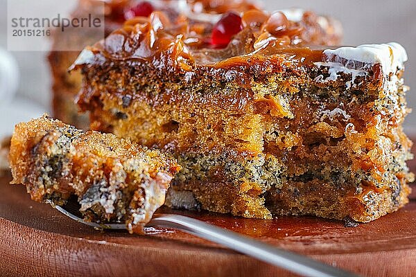 Ein Stück Kuchen mit Karamellcreme  geschnitten mit einem Löffel auf einem hölzernen Küchenbrett und einer Tasse Kaffee  brauner Holzhintergrund  Nahaufnahme  selektiver Fokus