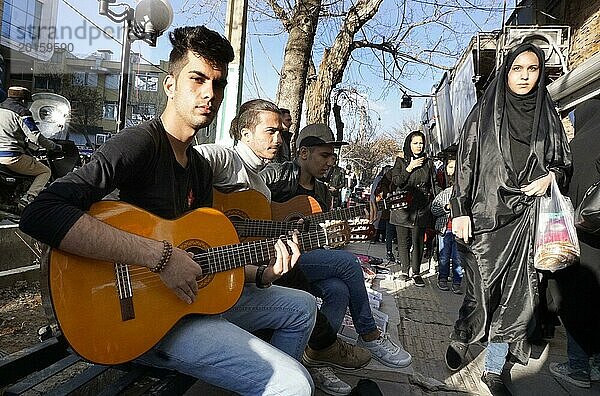 Junge iranische Straasenmusiker mit Guitarren in Arak  Iran  Frauen mit Tschador am 16.03.2019. Nach dem Rueckzug der USA aus dem internationalen Atomabkommen setzt das Land erneut Sanktionen gegen den Iran in Kraft