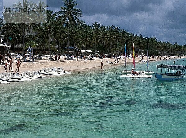 Viele Badeferiengäste betreiben Wassersport im Urlaub am Strand von Punta Cana. Viele Badeurlauber betreiben Wassersport im Urlaub am Strand von Punta Cana  retro  vintage  alt