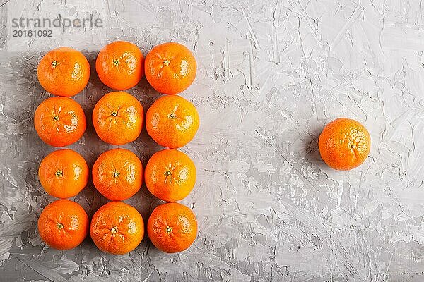 Reihen von Mandarinen  die ein Rechteck bilden  und eine Mandarine auf einem grauen Betonhintergrund  Draufsicht  flach gelegt