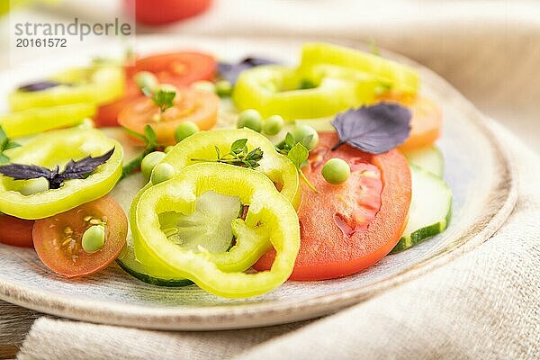 Vegetarischer Salat aus grünen Erbsen  Tomaten  Paprika und Basilikum auf weißem Holzhintergrund und Leinentuch. Seitenansicht  Nahaufnahme  selektiver Fokus