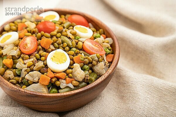 Mungobohnenbrei mit Wachteleiern  Tomaten und mikrogrünen Sprossen auf einem weißen Holzhintergrund und Leinenstoff. Seitenansicht  Nahaufnahme  selektiver Fokus